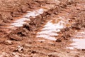 Wheel trace on road, puddle and mud after rain. Traces on soil of tractor, excavator, car, automotive tire tracks on muddy trail. Royalty Free Stock Photo