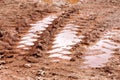 Wheel trace on road, puddle and mud after rain. Traces on soil of tractor, excavator, car, automotive tire tracks on muddy trail. Royalty Free Stock Photo