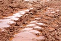 Wheel trace on road, puddle and mud after rain. Traces on soil of tractor, excavator, car, automotive tire tracks on muddy trail. Royalty Free Stock Photo