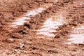 Wheel trace on road, puddle and mud after rain. Traces on soil of tractor, excavator, car, automotive tire tracks on muddy trail.