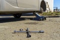 Wheel wrench and nuts next to jacked up car without a wheel in tire service