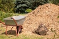 wheelbarrow in front of a large mountain of fresh sawdust in the park