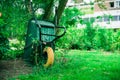 Wheelbarrow stands against a tree, Communal city garden