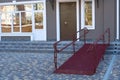 Wheelchair access ramp for entrance of residential multistory building, city street and tiles sidewalk