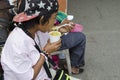 Wheelchair female Beggar eating a cup of gruel