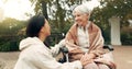 Wheelchair, park and a senior woman with a disability talking to her nurse during a walk together outdoor. Healthcare