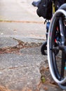 Wheelchair wheels up against cracks in broken sidewalk