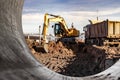 A wheeled excavator loads a dump truck with soil and sand. An excavator with a high-raised bucket against a cloudy sky View from Royalty Free Stock Photo