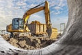 A wheeled excavator loads a dump truck with soil and sand. An excavator with a high-raised bucket against a cloudy sky View from Royalty Free Stock Photo