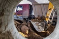 A wheeled excavator loads a dump truck with soil and sand. An excavator with a high-raised bucket against a cloudy sky View from Royalty Free Stock Photo