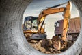 A wheeled excavator loads a dump truck with soil and sand. An excavator with a high-raised bucket against a cloudy sky View from Royalty Free Stock Photo