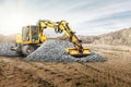 A wheeled excavator works in a sand pit against the sky. Spreads crushed stone or gravel with a wide bucket. Powerful earthmoving Royalty Free Stock Photo