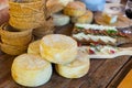 Wheels of hard goat cheese stacked on table during degustation