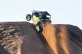 The wheels of a side-by-side spray gravel going over a hill