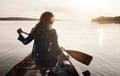 This is where I found peace. Rearview shot of a young woman enjoying a canoe ride at the lake.