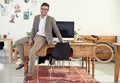 This is where I make magic happen. Portrait of a casually-dressed young man sitting on his desk in an office. Royalty Free Stock Photo