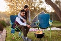 Where theres smoke theres dinner. a young couple roasting marshmallows while camping outside.