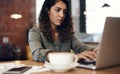 Where theres wifi, theres a blogger. a young woman using a laptop while working in a cafe.