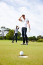 Wheres the breeze when you need one. two golfers looking disappointed as the golf ball misses the hole.