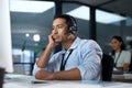 Wheres a call transfer when you need one. a young man using a headset and looking bored in a modern office.