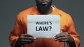 Wheres law question on cardboard in hands of Afro-American prisoner, disorder