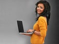 Wherever I go my laptop goes with me. Studio shot of a young woman using a laptop against a gray background. Royalty Free Stock Photo