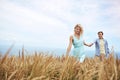 Wherever she leads, he will follow. a young couple in a field on a sunny day.