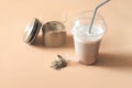Whey drink in plastic cup and a jar with chocolate protein powder and a scoop on a table. protein supplement for healthy muscle