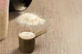 Whey Protein. Dropped black jar and spilled powder. Yellow measuring scoop. Selective focus and wooden table. Royalty Free Stock Photo