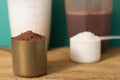 Whey Protein. Front view of two scoops with chocolate and vanilla powder and shakers on rustic wooden table. Solid color: green. Royalty Free Stock Photo