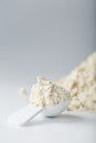 Whey protein isolate with a measuring spoon on a white background.
