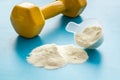 Whey protein powder in plastic measuring scoop near dumbbells on blue background Royalty Free Stock Photo