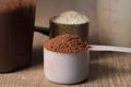 Whey Protein. Two scoops with vanilla and chocolate flavour powder, shaker. Wooden table. Close up, texture. Royalty Free Stock Photo