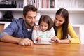 Which one do you want daddy. A little girl playing on a tablet with her parents. Royalty Free Stock Photo