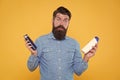 Which soap best. Bearded man hold soap bottles yellow background. Hipster choose liquid soap. For washing in bath or Royalty Free Stock Photo