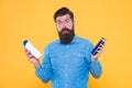 Which soap best. Bearded man hold soap bottles yellow background. Hipster choose liquid soap. For washing in bath or Royalty Free Stock Photo