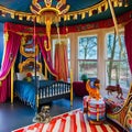 A whimsical circus-themed bedroom with a carousel bed, circus tent drapes, and circus animal wall murals4