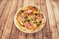 Whimsical Italian gastronomy pizza prepared with mozzarella cheese, oven-roasted Italian ham, artichokes