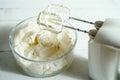 Whipped cream in a bowl and electric hand mixer on bright table. Royalty Free Stock Photo