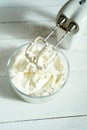 Whipped cream in a bowl and electric hand mixer on bright table. Royalty Free Stock Photo