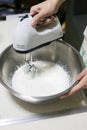 Whipped cream in bowl with electric hand mixers are used to make whipped cream
