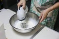 Whipped cream in bowl with electric hand mixers are used to make whipped cream