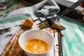 Whipped with a fork and mixed raw egg broken into a white bowl with yolk and protein, next to the shell, fork and towel