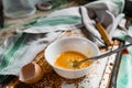 Whipped with a fork and mixed raw egg broken into a white bowl with yolk and protein, next to the shell, fork and towel Royalty Free Stock Photo