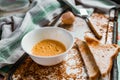 Whipped with a fork and mixed raw egg broken into a white bowl with yolk and protein, next to the shell, fork and towel