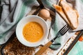 Whipped with a fork and mixed raw egg broken into a white bowl with yolk and protein, next to the shell, fork and towel