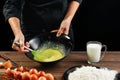 Whipping eggs. Chef hands close-up whisk eggs on a black background. Natural light, slightly toned image. Copy space Royalty Free Stock Photo