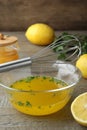 Whisk and bowl with lemon sauce on wooden table. Delicious salad dressing Royalty Free Stock Photo