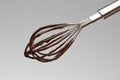 Whisk with liquid melted chocolate on light grey background Royalty Free Stock Photo