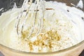 Whisk mixes a hearty dip of goat cream cheese with ground nuts and pepper in a glass bowl, selected focus
